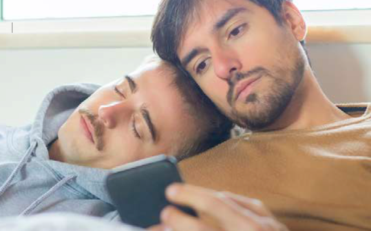 Two men sitting on a couch looking at a phone together