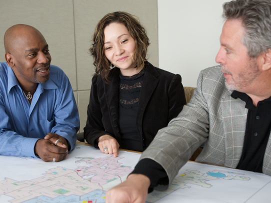 three people at a table looking at a map