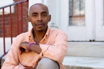 African American man sitting on a stoop looking thoughtful