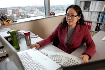 Asian American woman at desk looking at computer
